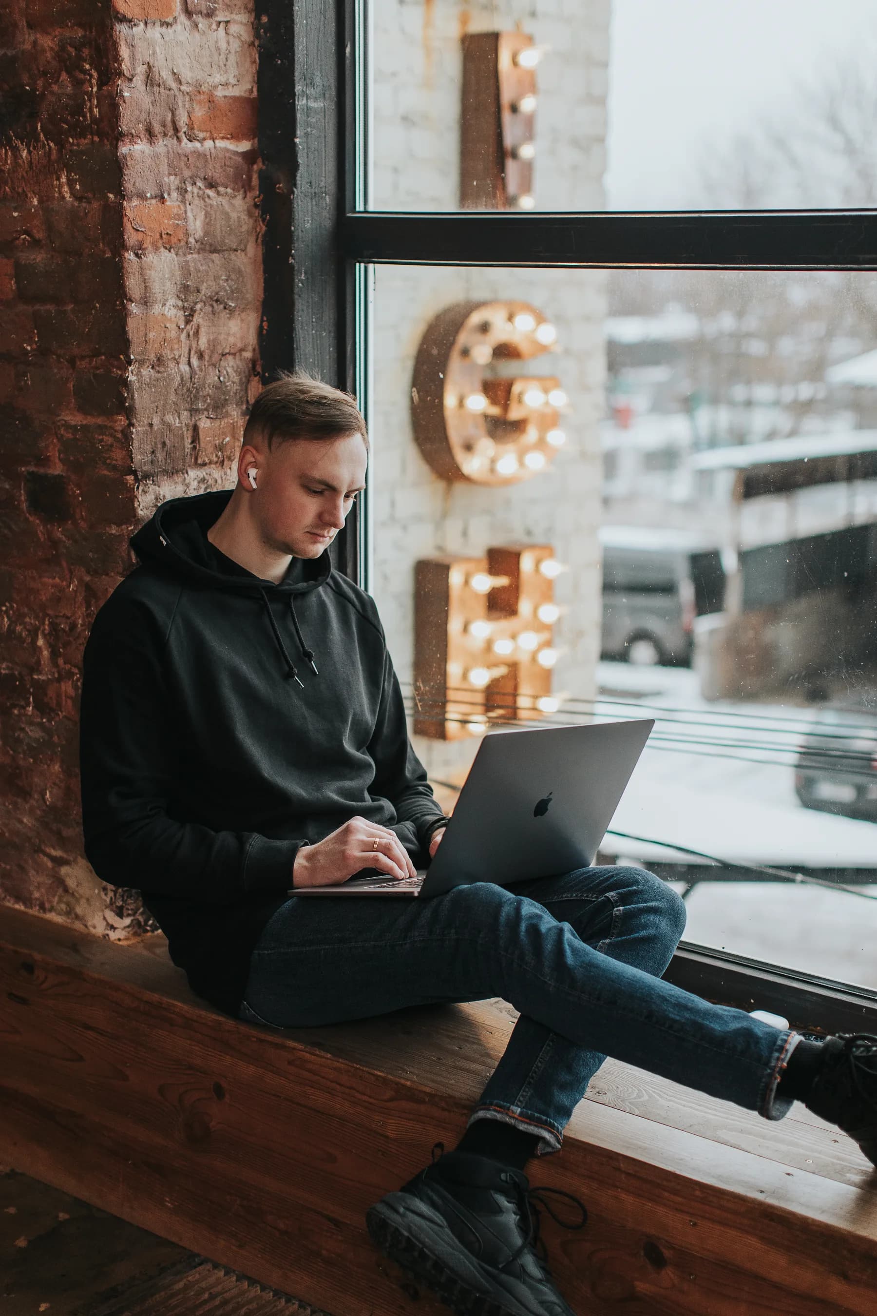 Pavel Bileush working on a laptop near a large studio window.